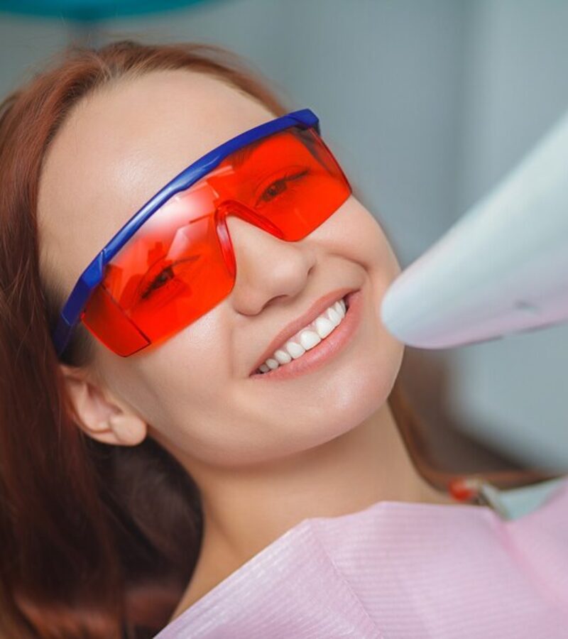 beautiful-girl-red-protective-glasses-sitting-blue-chair-office-dentist_98890-356